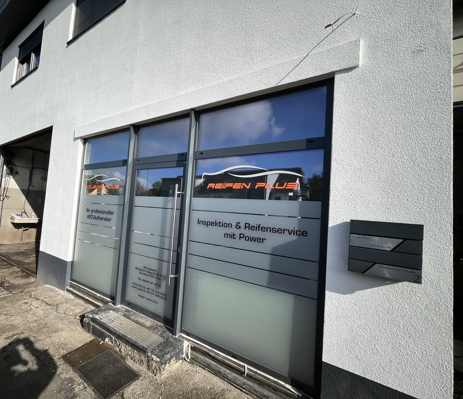 Eingang von Clean Plus mit Öffnungszeiten und Schriftzug „Ihr professioneller KFZ-Aufbereiter“